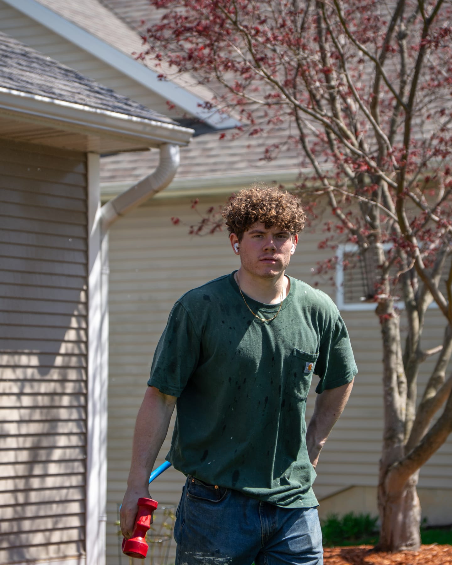 Elevation technician holding a soft-wash spray nozzle in front of a home after washing the siding