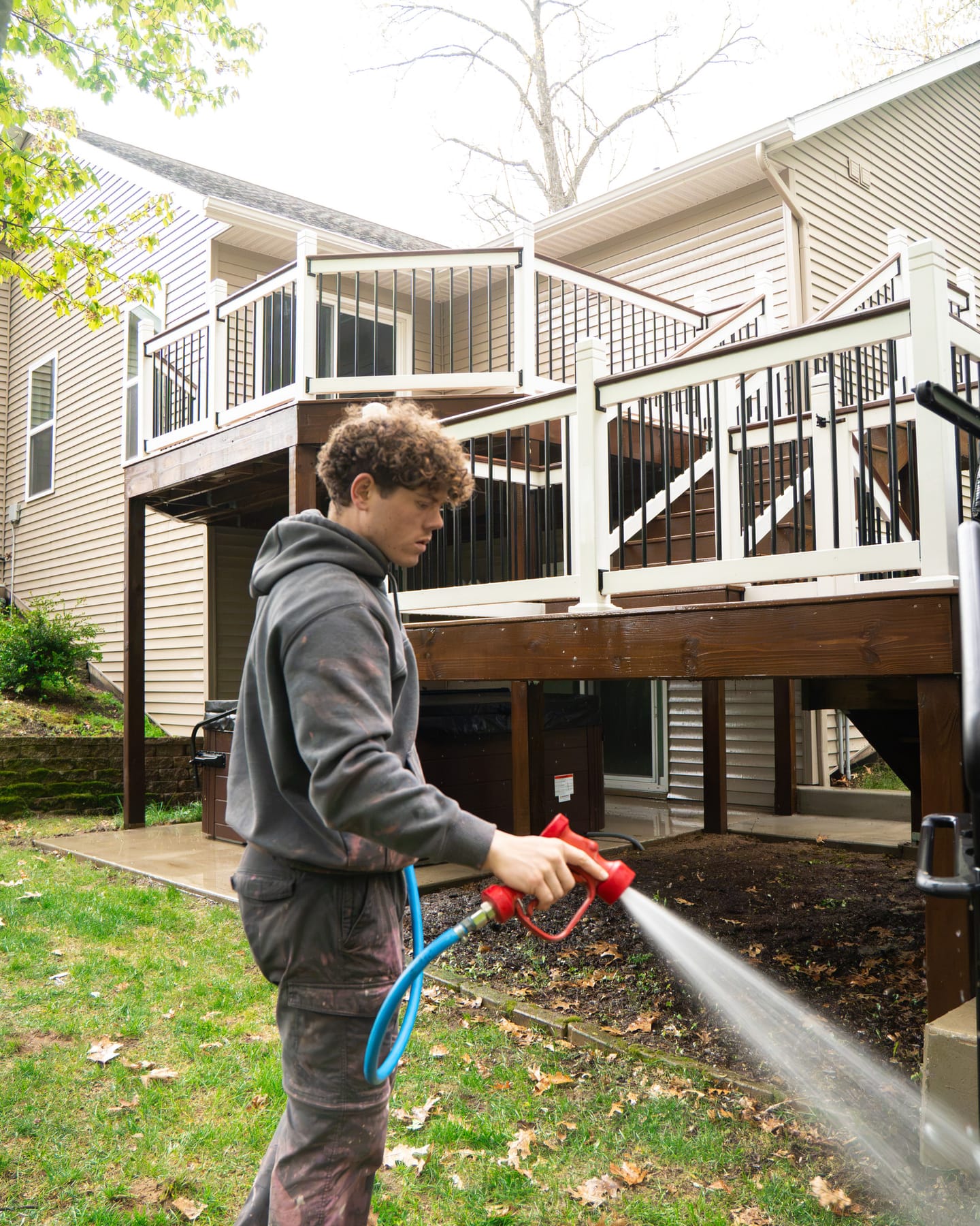 Technician washing beside a two-tier stained wood deck with white vinyl railings
