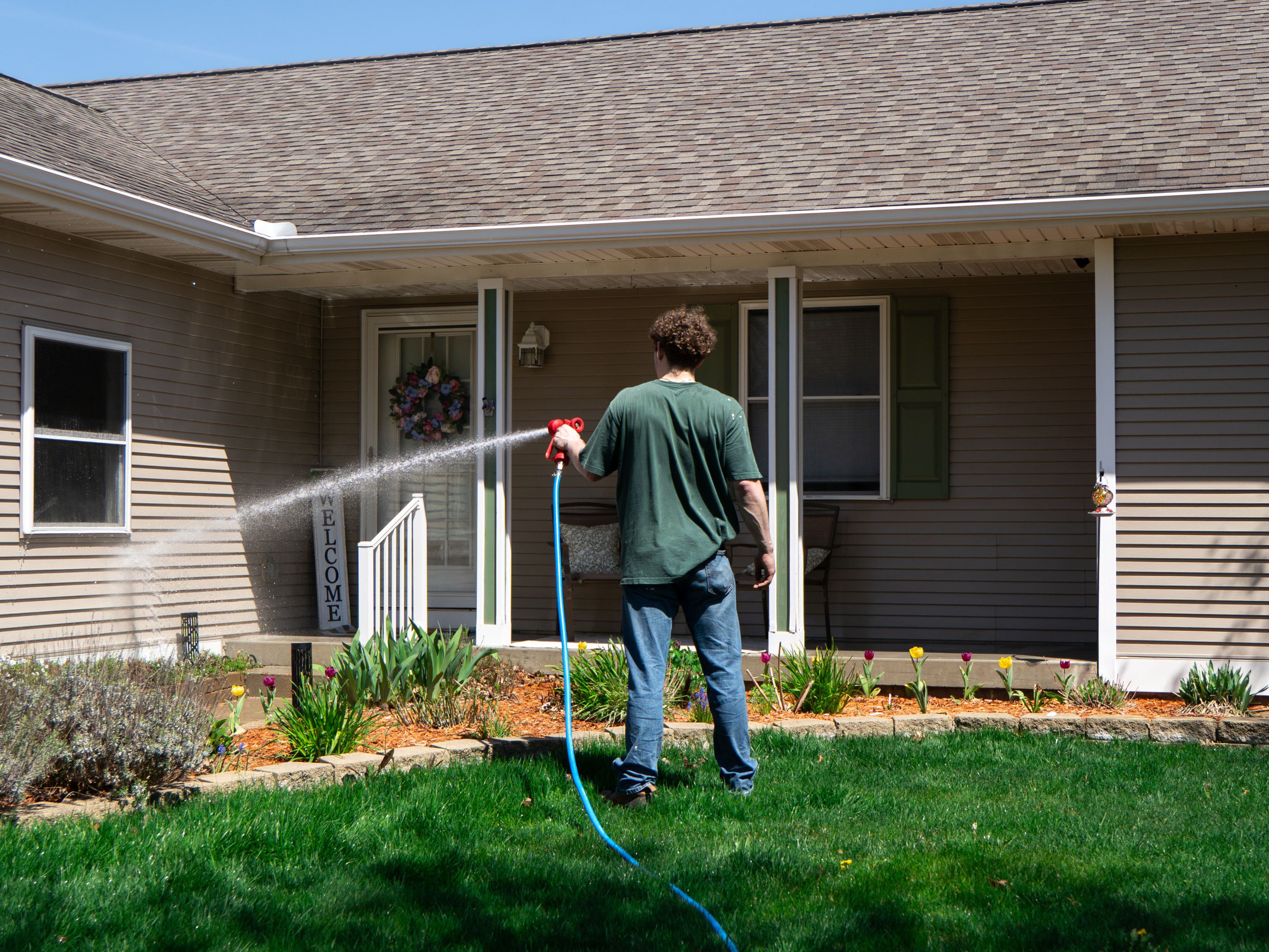 Elevation technician soft-washing the front of a home in the Wyoming area from ground level